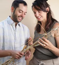 Two people smiling with a wheat branch